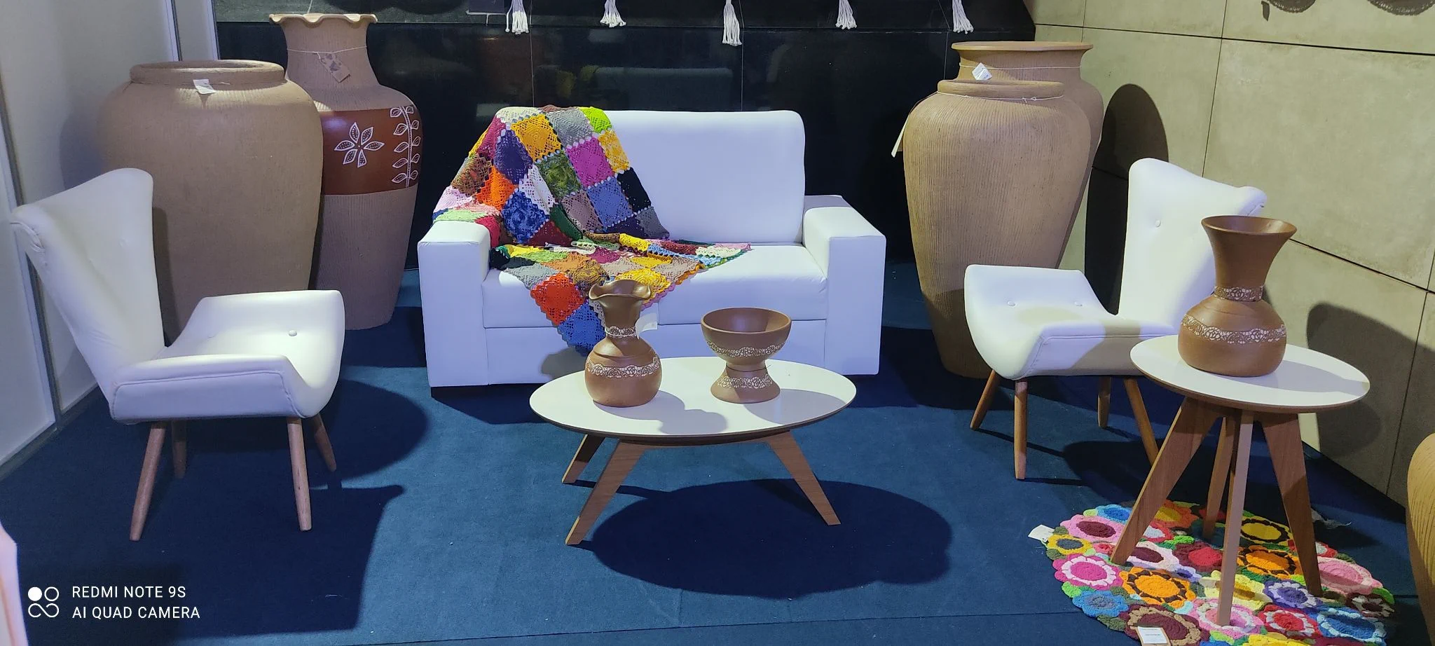 Lounge com sofá branco, poltronas, mesas e vasos decorativos